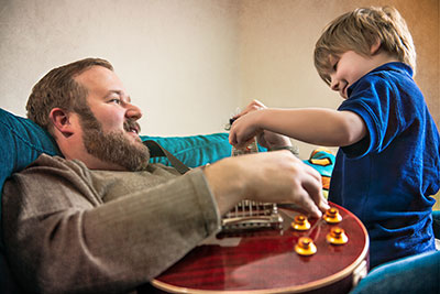 Justin Vickery playing guitar with son