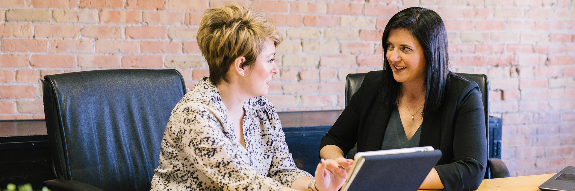 Two women looking at a tablet computer talking