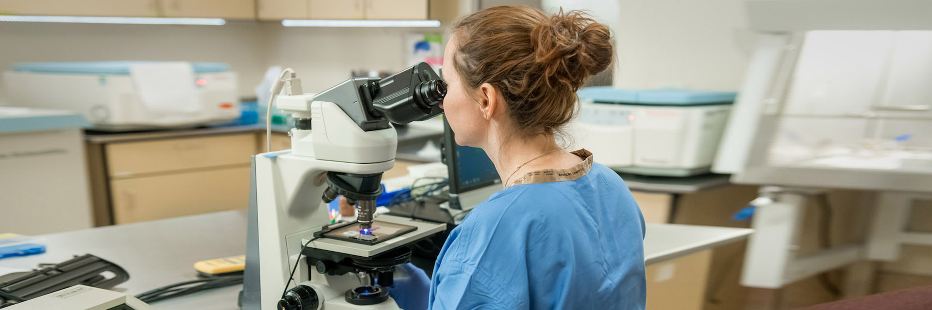 Female Researcher Looking Through Microscope