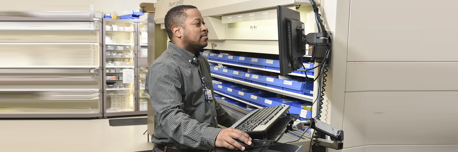 Pharmacy staff member working at a medication storage workstation