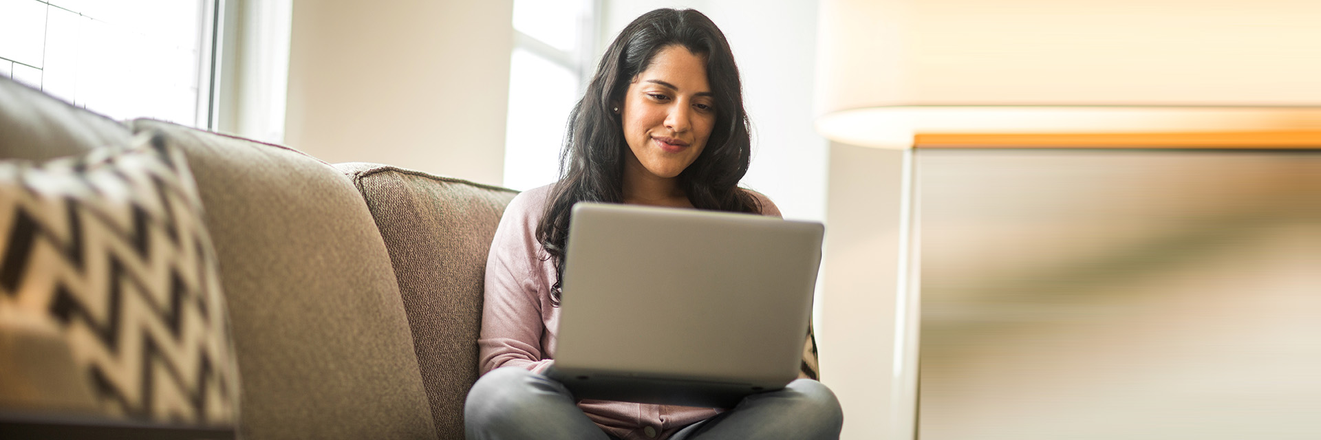 Woman sitting on couch using laptop