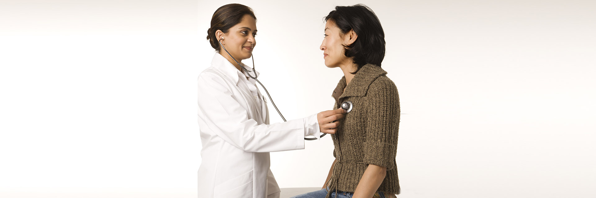 Doctor using stethoscope to check female patient