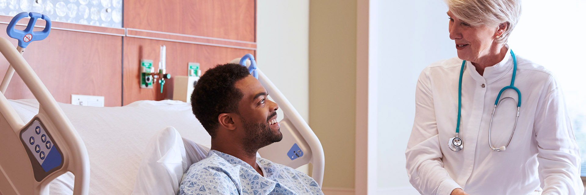 Man in hospital bed talking to physician