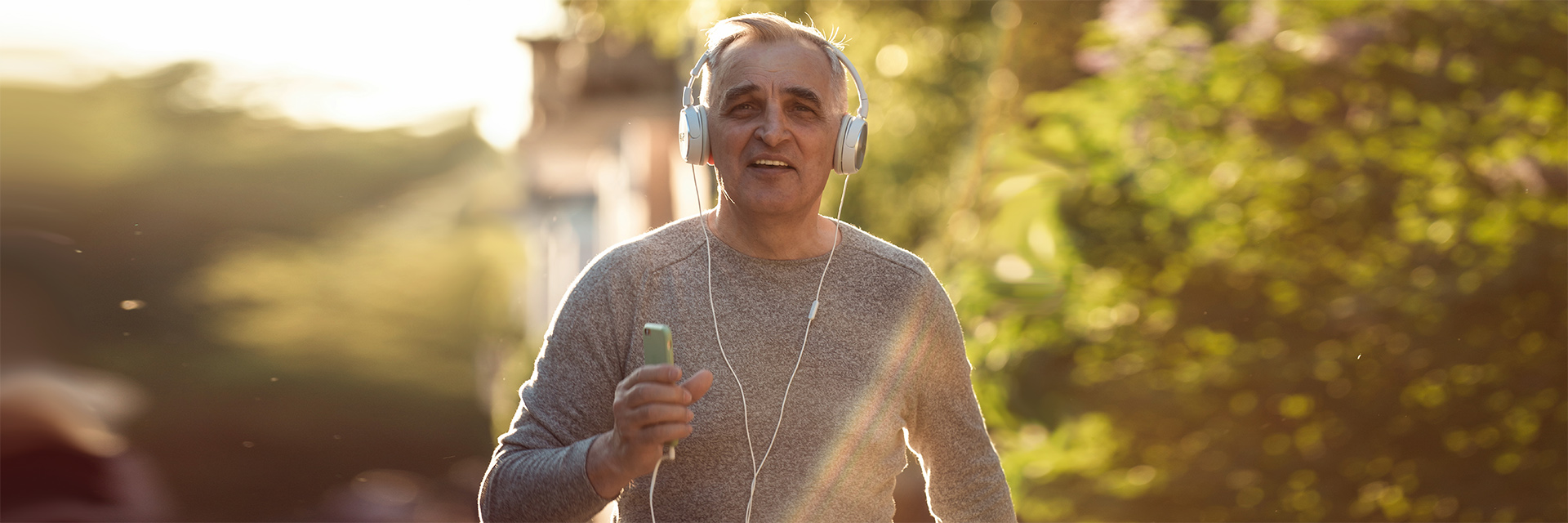 Mature man running while on phone with headphones