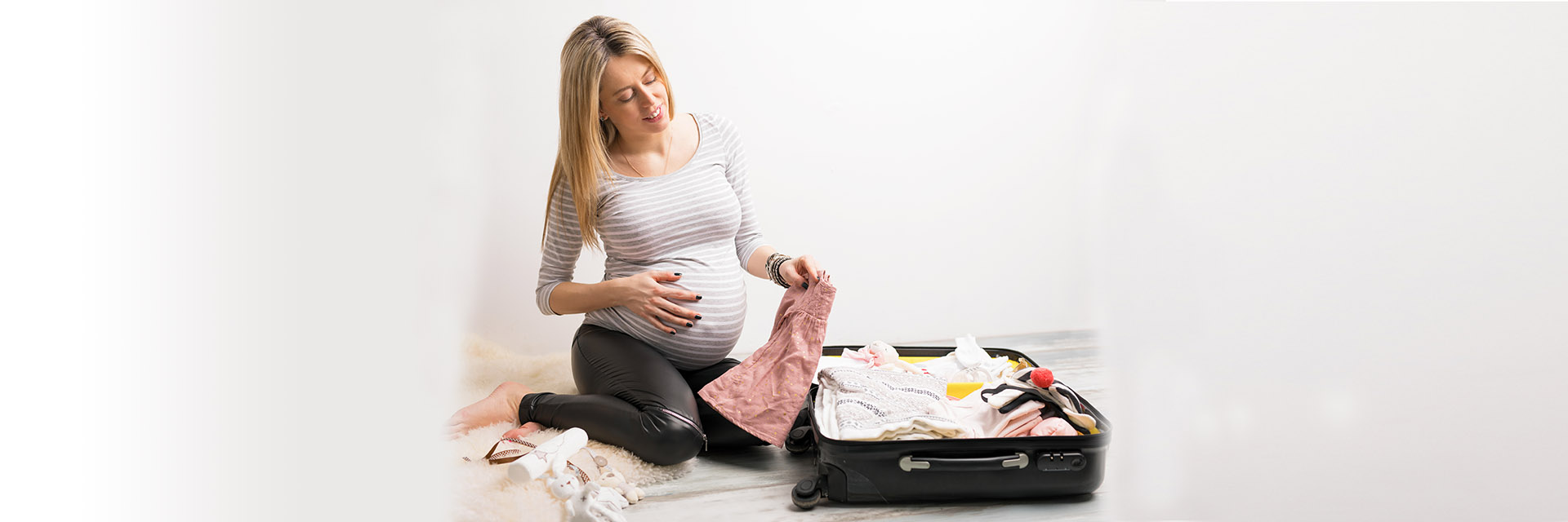 Pregnant woman sitting on floor and packing an overnight bag