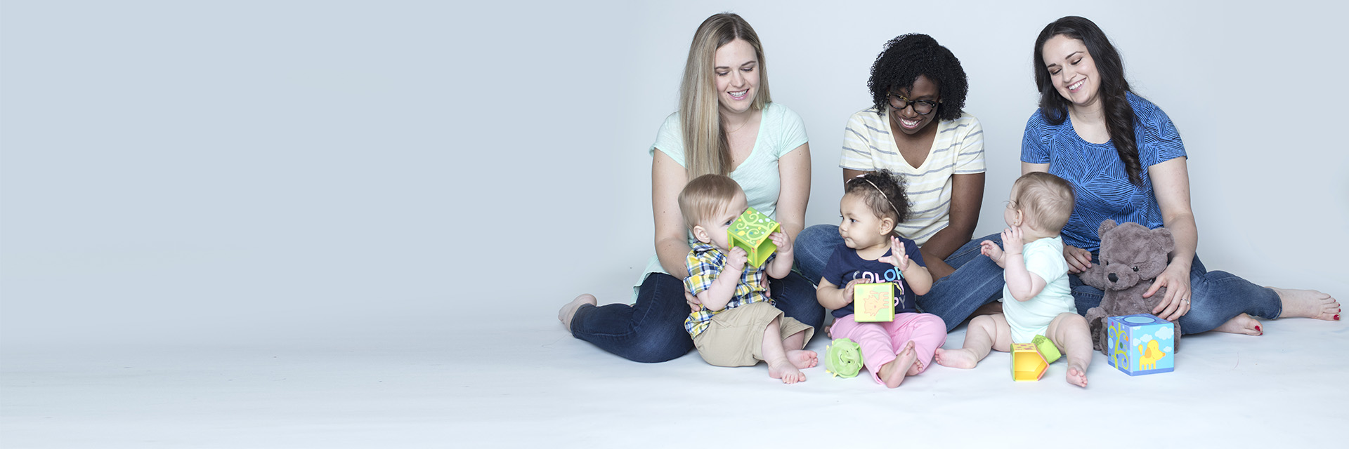 Three moms sitting on the floor with their three babies