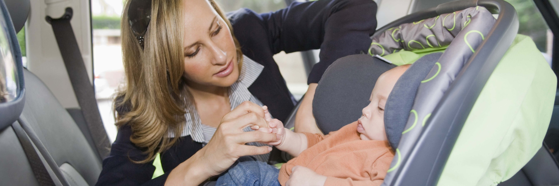 Mother buckling baby in car seat