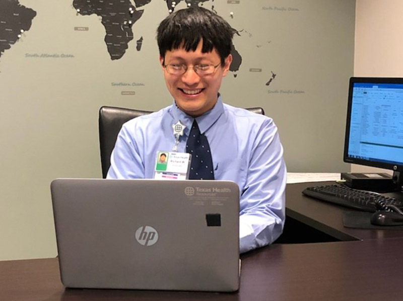 Academic Volunteer Sits behind desk in front of world map