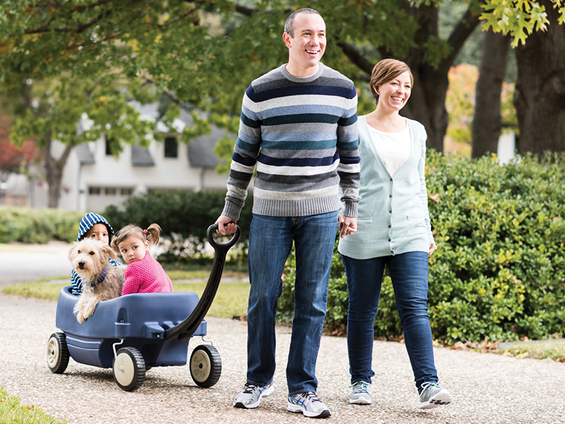 Family walks outside pulling their kids in a wagon 