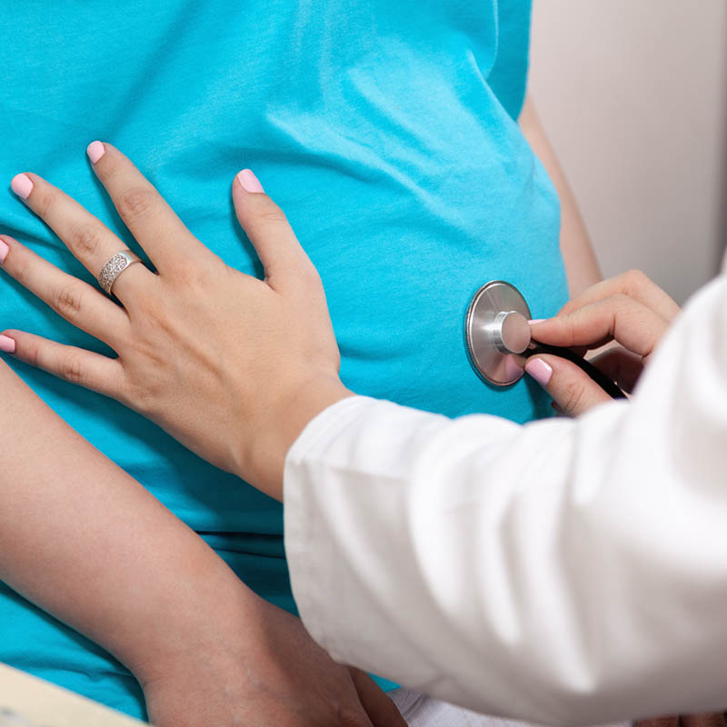 Gynecologist Checking Pregnant Woman's Belly With Stethoscope