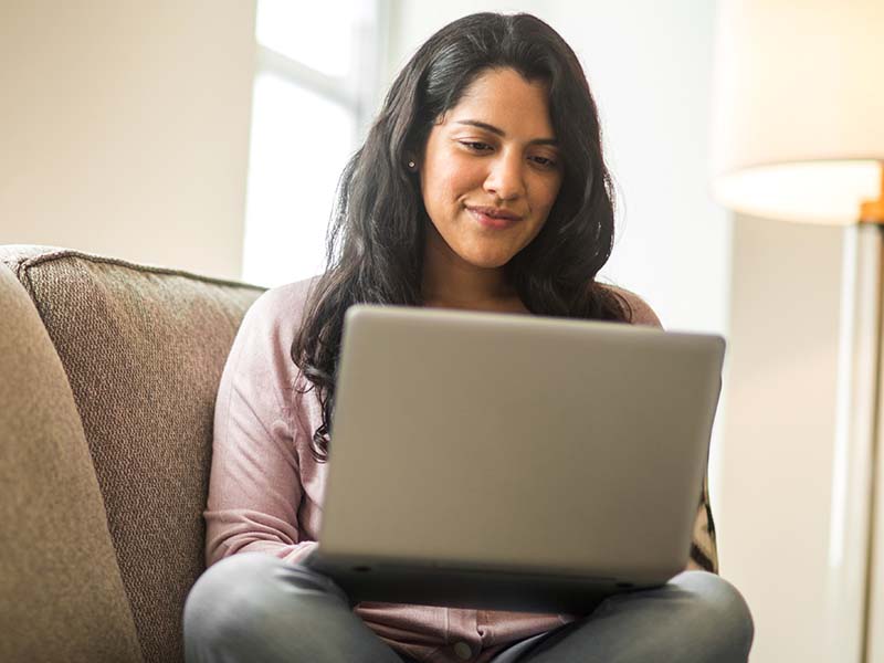 Woman sitting on couch using laptop