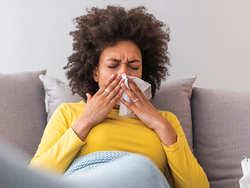 Woman sneezing on couch