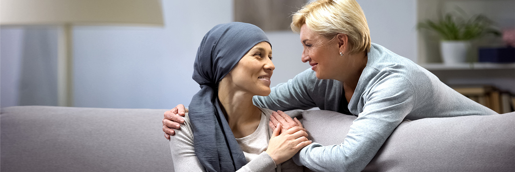 Woman consoling woman, cancer patient in head scarf 