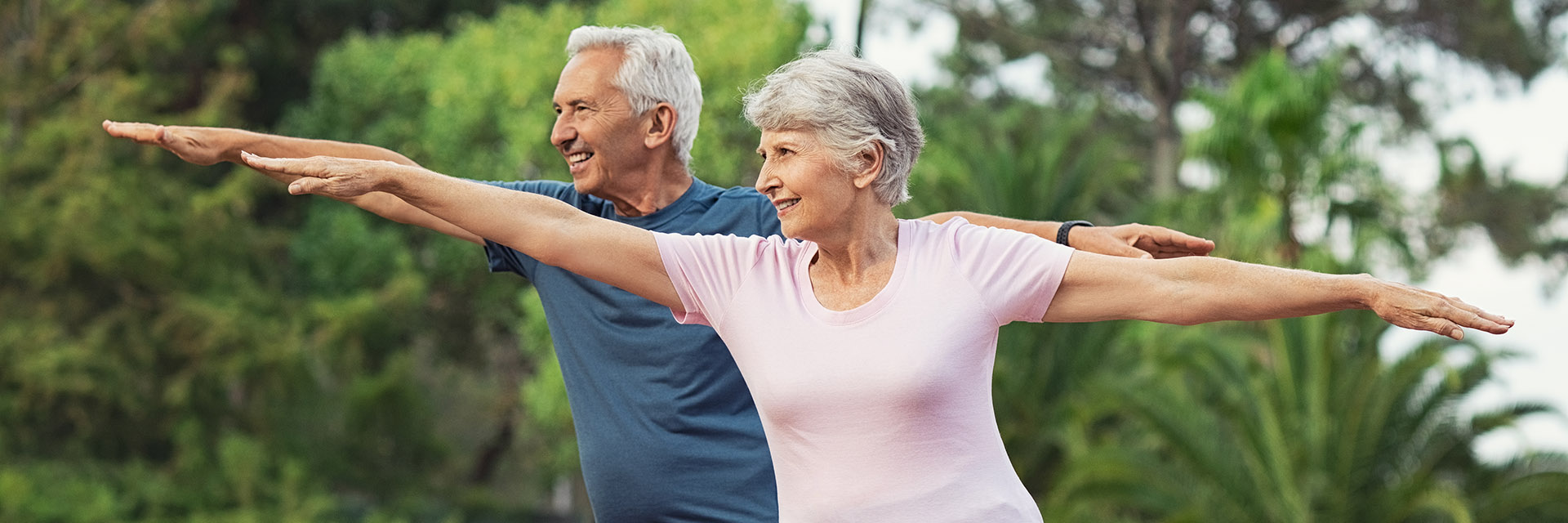 Mature couple doing yoga Pilates pose outdoors