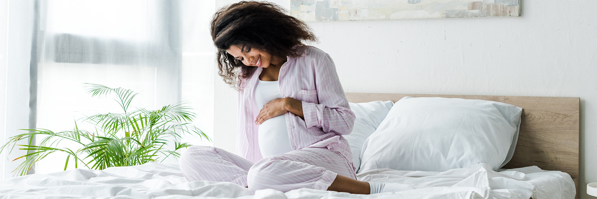 Pregnant woman on bed rubbing her stomach