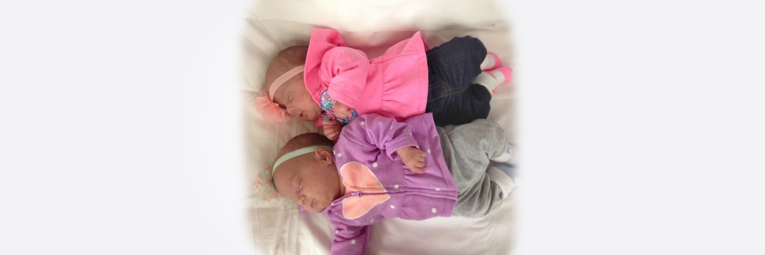Two infants in pink and purple clothes