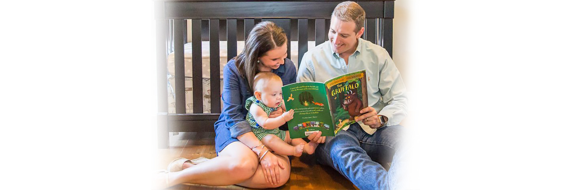New parents reading books to an infant on the floor