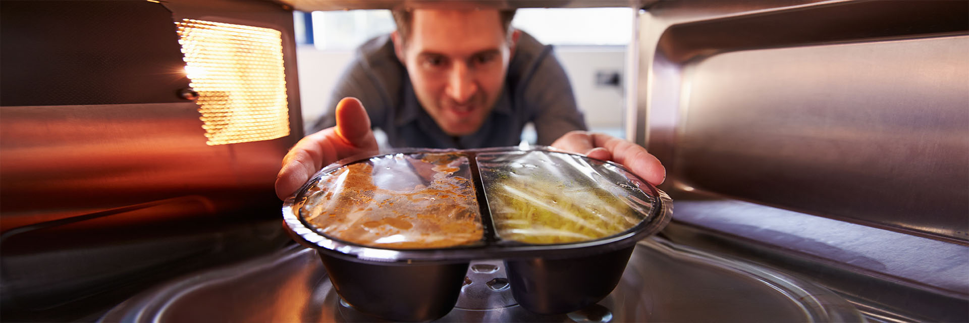 Man putting TV dinner into microwave