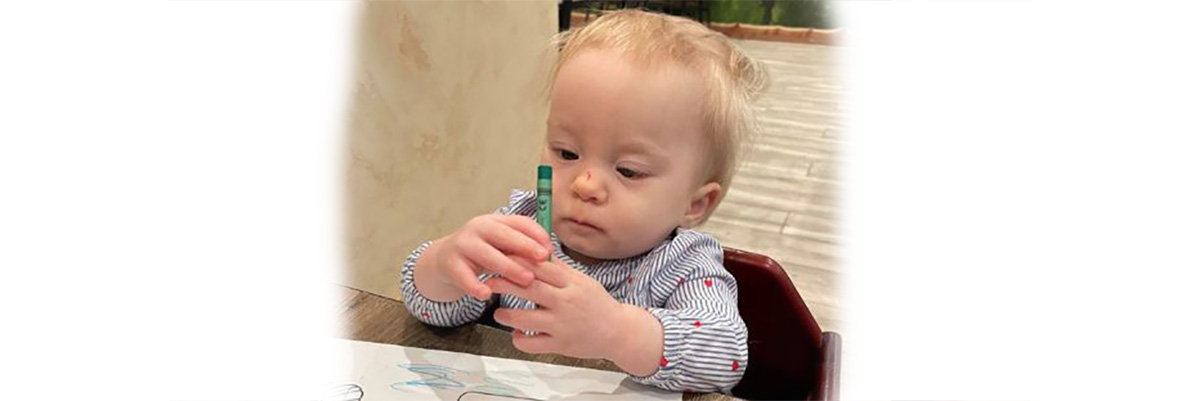 Infant holding a crayon at the table