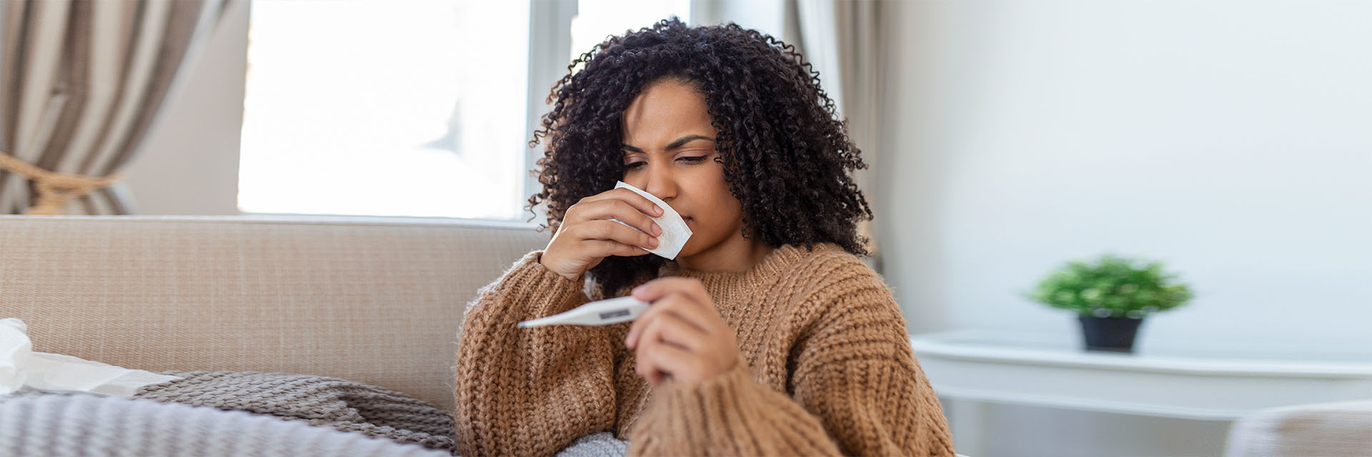 Woman sick on her couch taking her temp