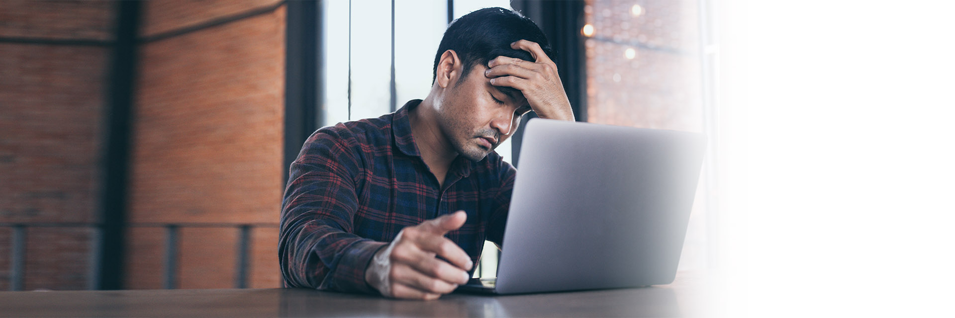 Man holding his head looking at laptop