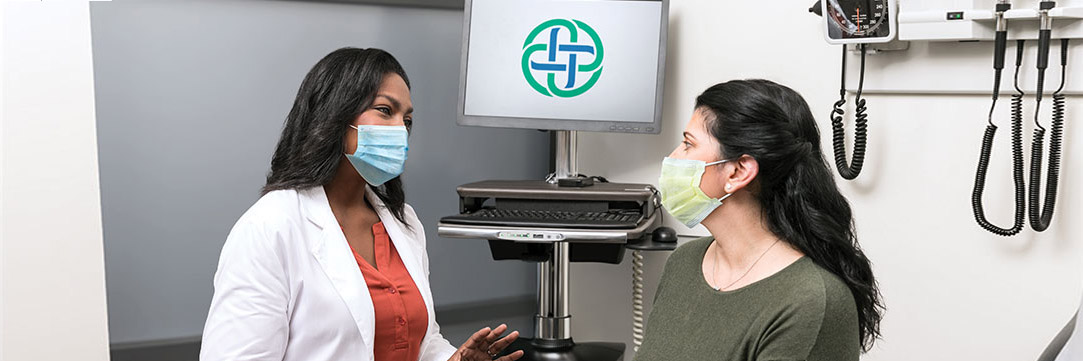 Masked female patient talking to female provider