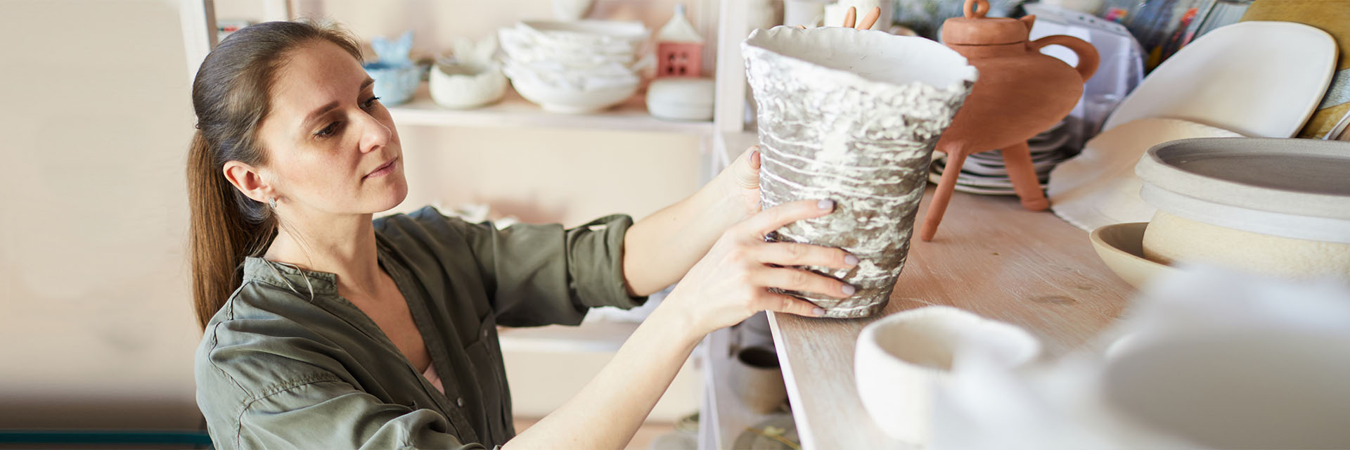 Woman in pottery storage room checking vase