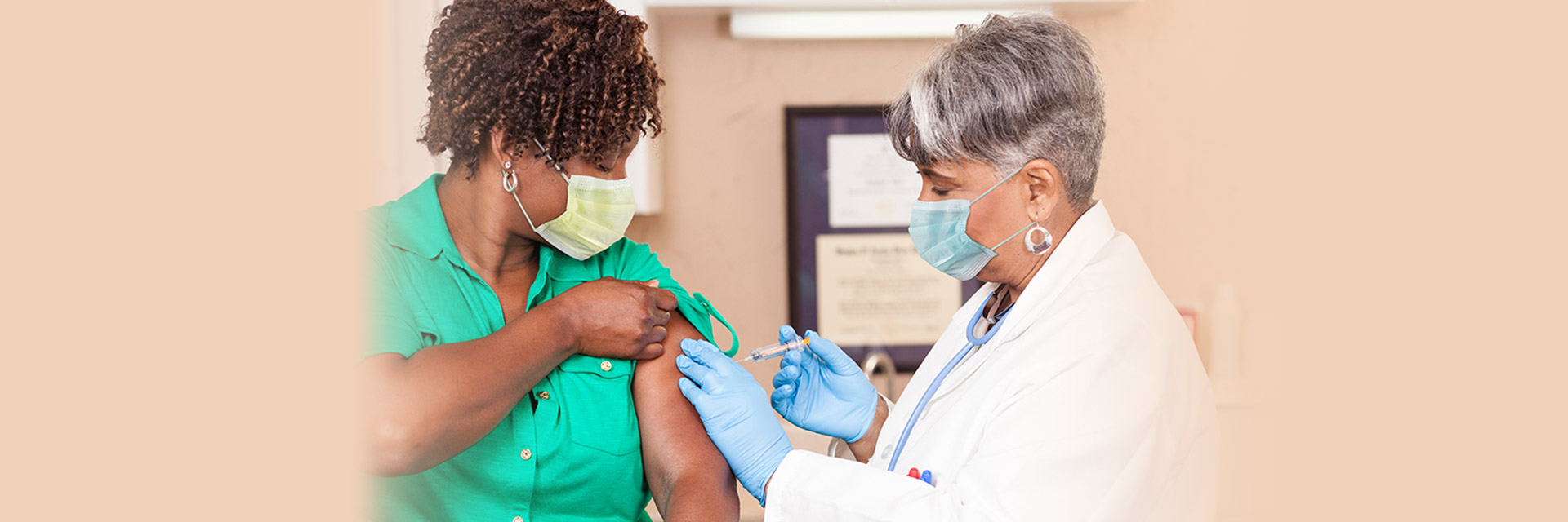 Masked provider giving injection in arm to masked patient