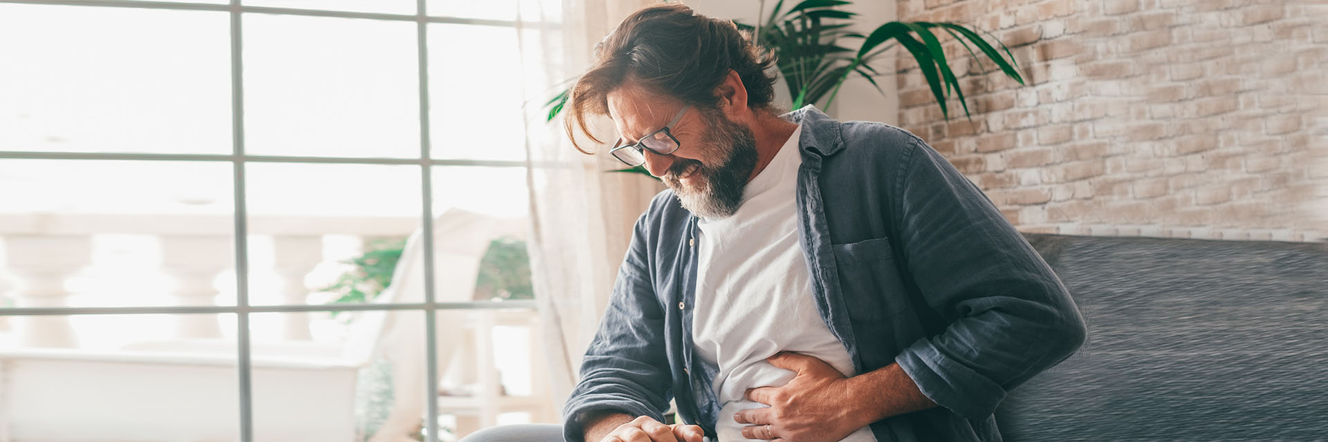 Man sitting on couch clutching his stomach