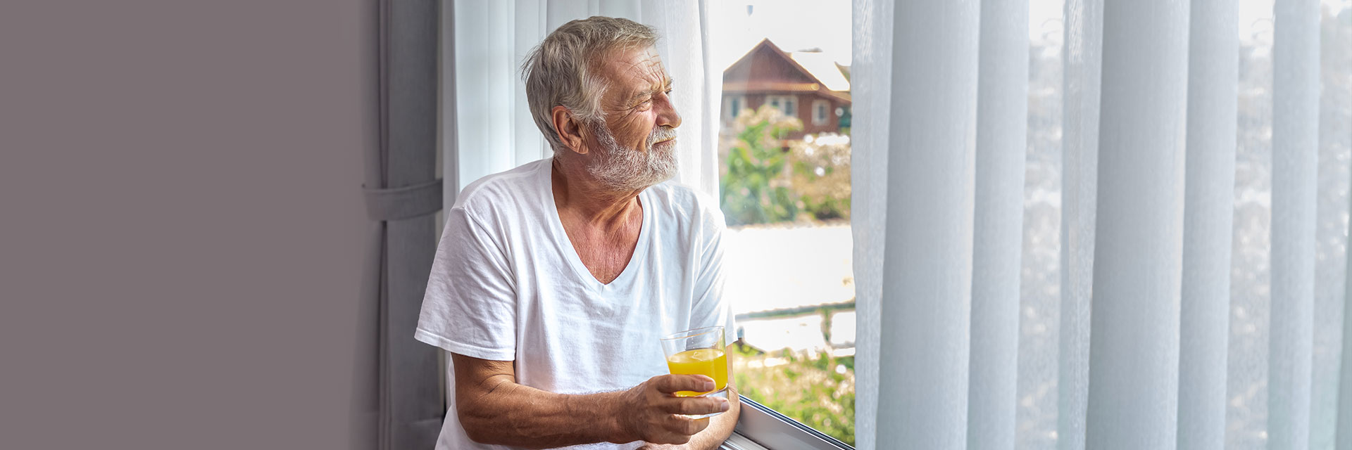 Man drinking juice looking out of window