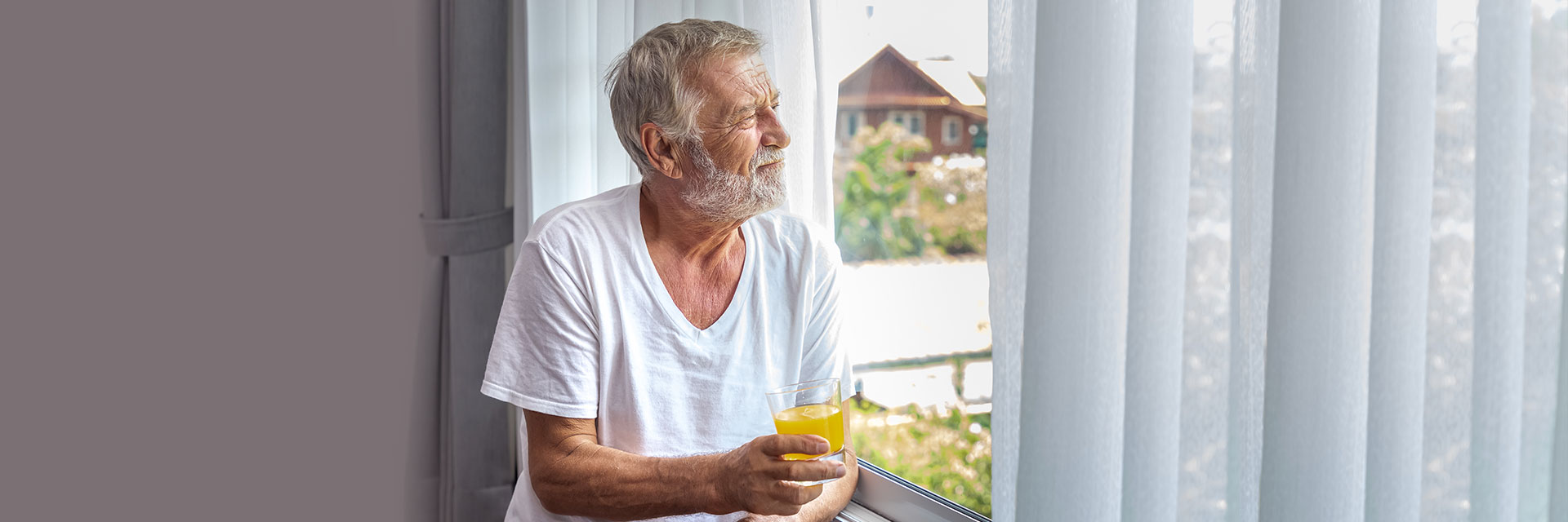 Man drinking juice looking out of window 