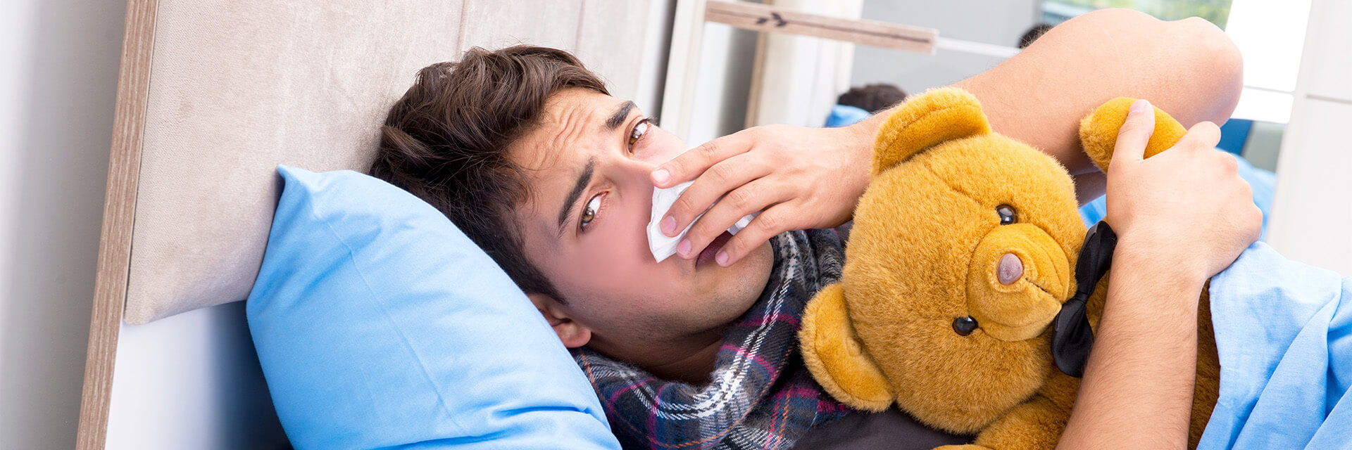 Sick man in bed holding teddy bear