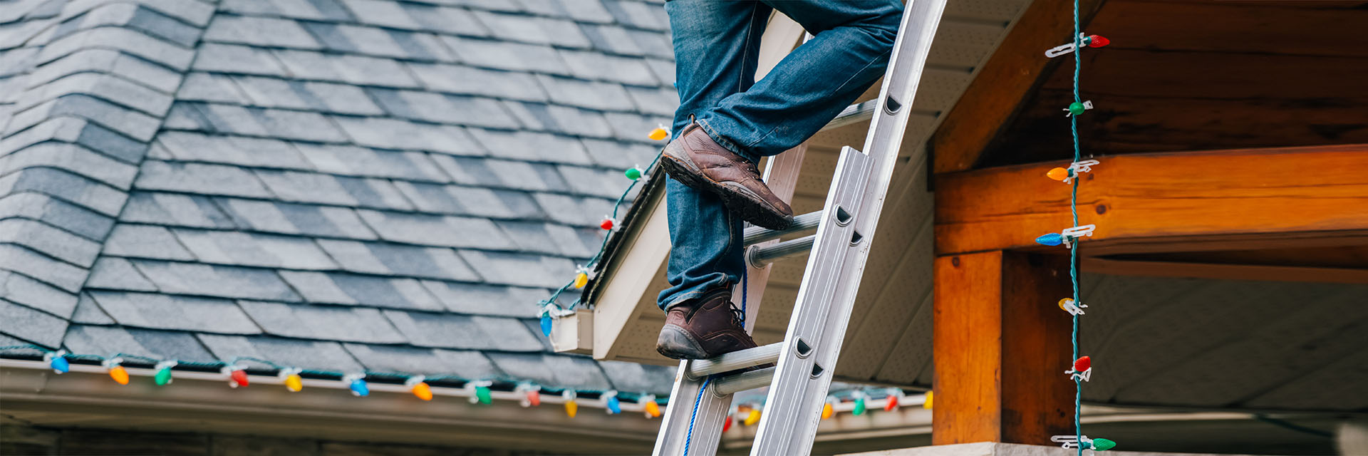 Man standing on ladder hanging Christmas lights