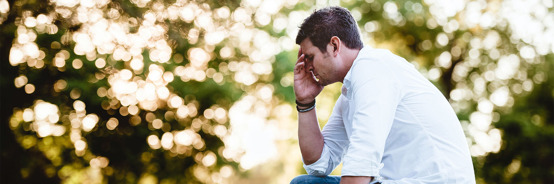 Man outdoors holding head