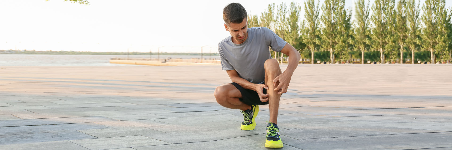Man rubbing his leg outdoors after exercise