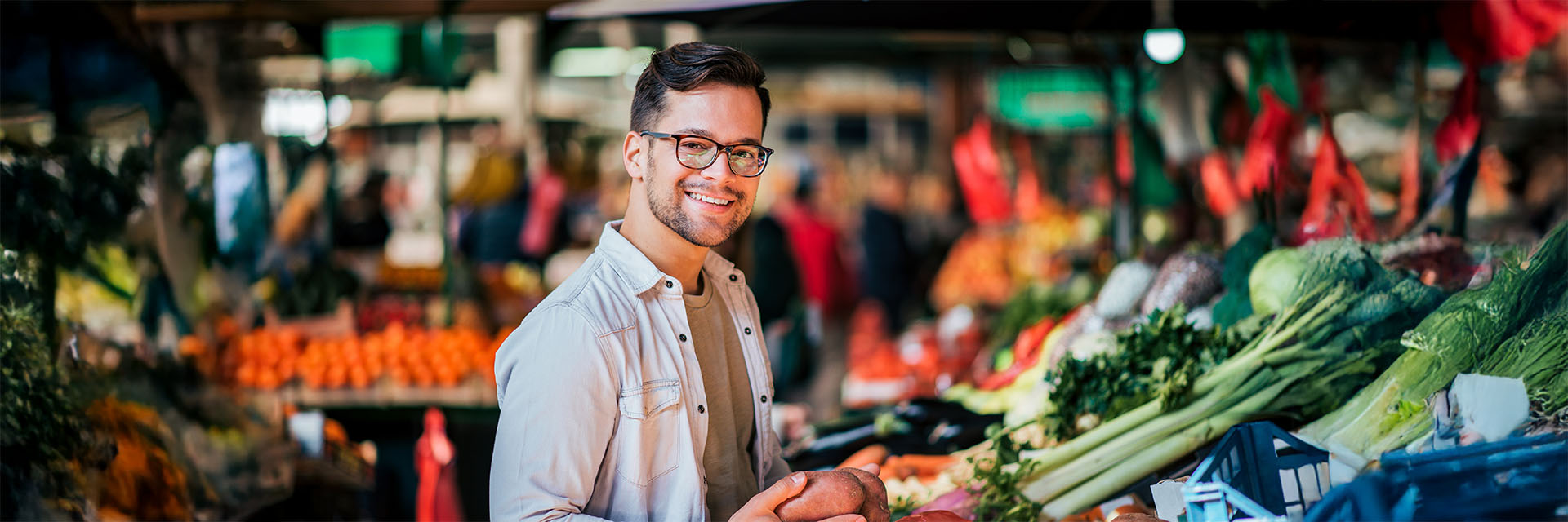 Man smiling at an outdoor vegetable market