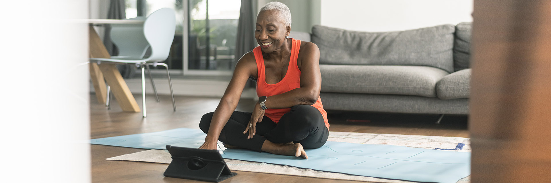 Mature woman sitting on a yoga mat looking at her tablet