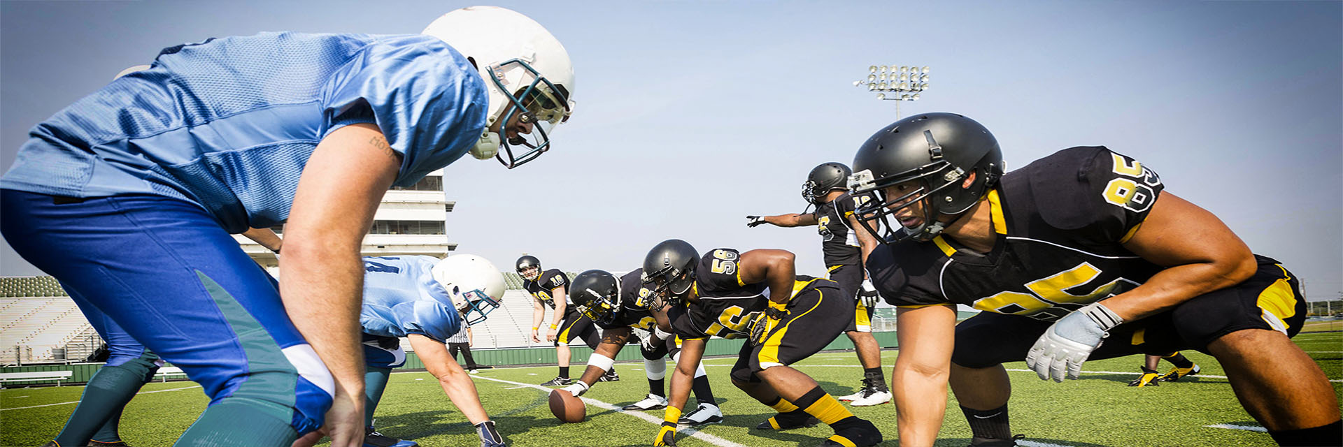 Men playing football outdoors in a 3 point stance