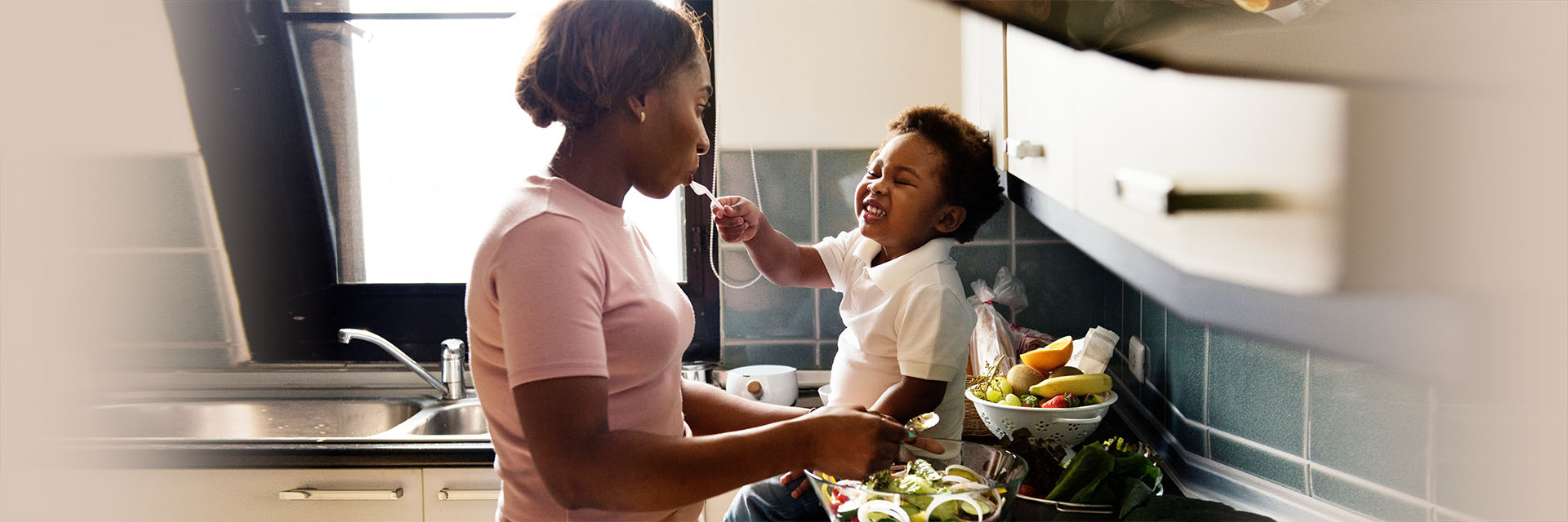 Mom cooking while playing with toddler son