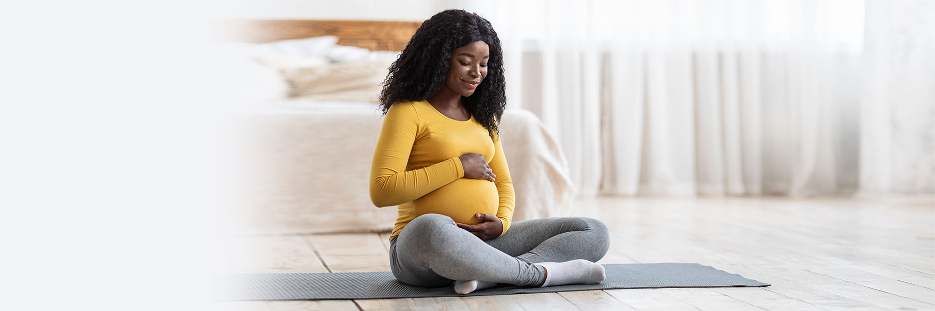 Pregnant woman sitting on a yoga mat and holding her belly