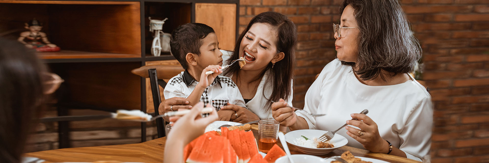 Mother feeding her son at the dinner table