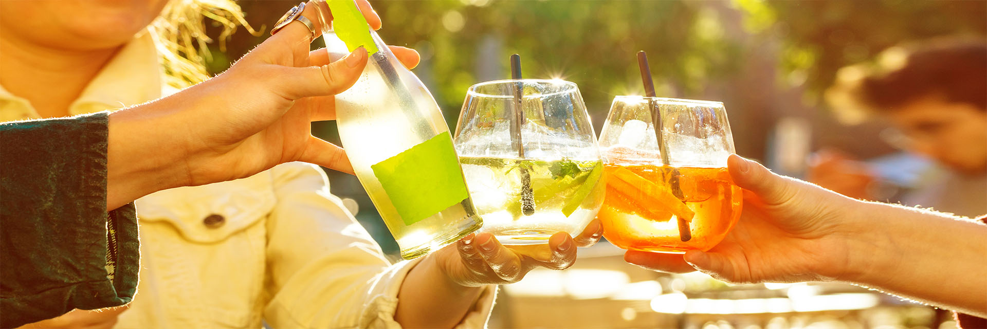 Multicolor drinks in glasses being held outdoors