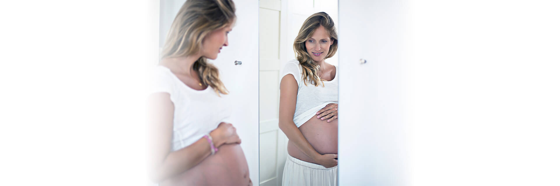 Pregnant woman in the mirror holding her belly