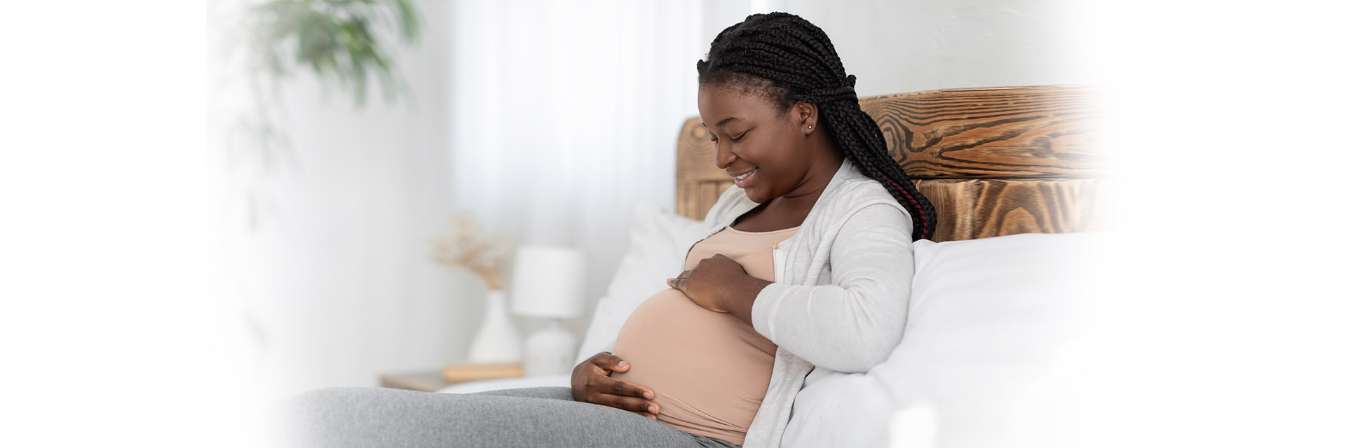 Pregnant woman holding her belly in bed