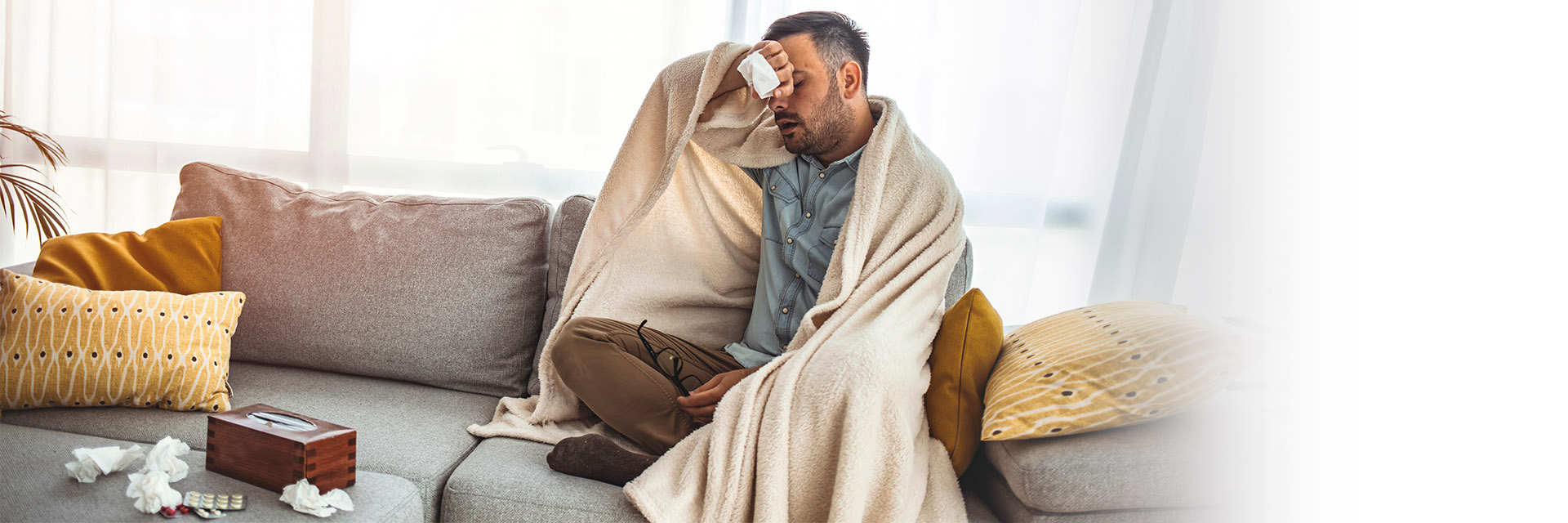 sick man wrapped in blanket on couch