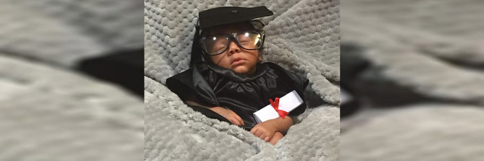 Infant bot in the N I C U dressed in cap and gown