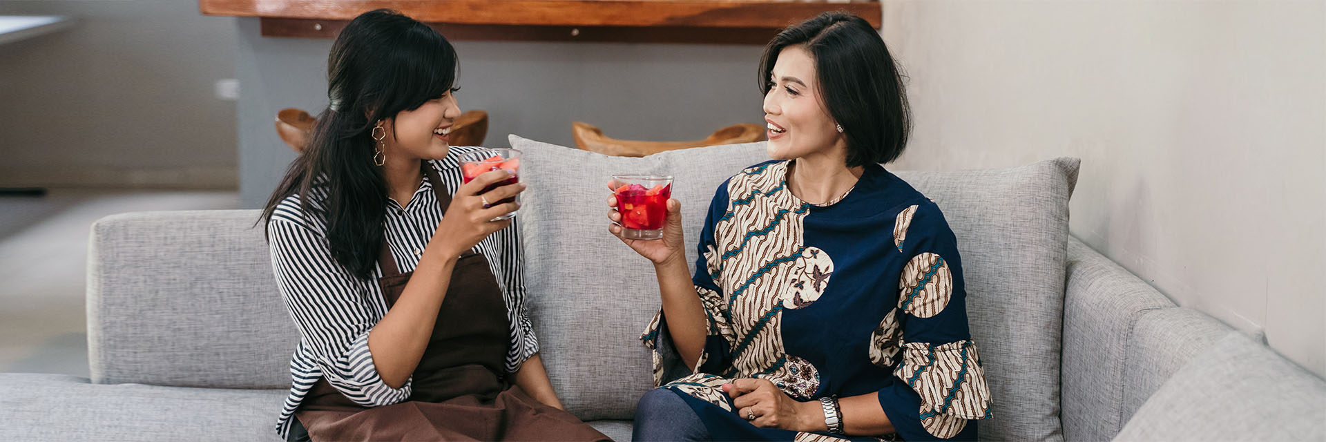 2 women drinking juice on the couch
