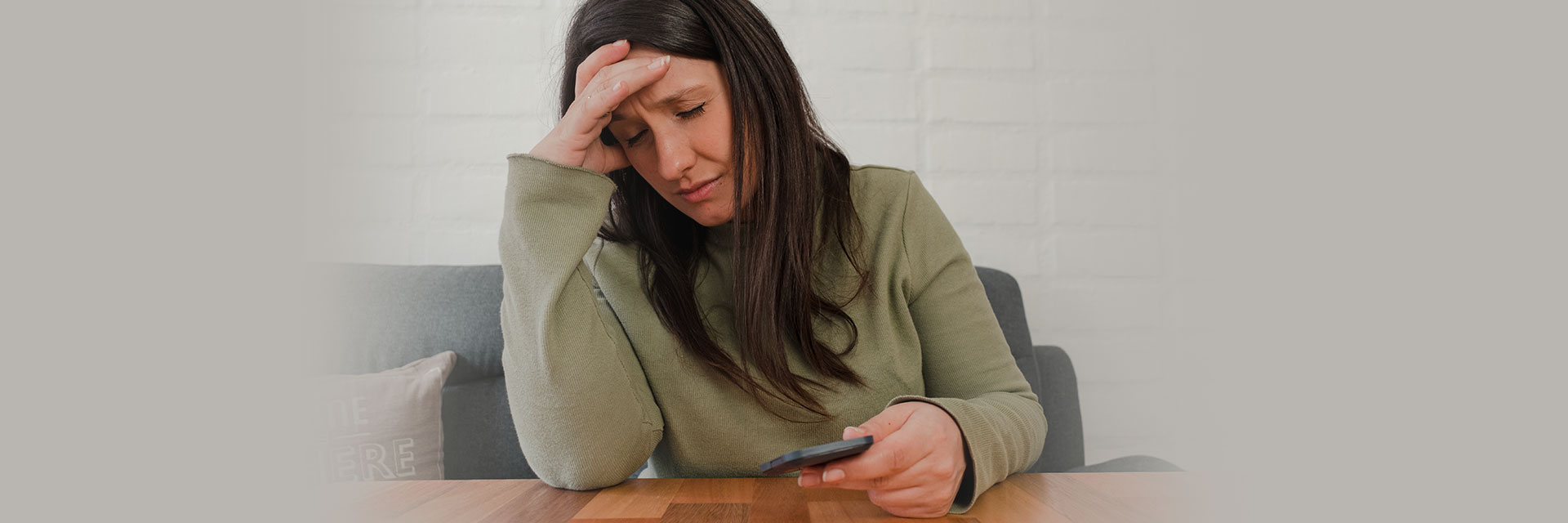 Woman holding head looking at her phone