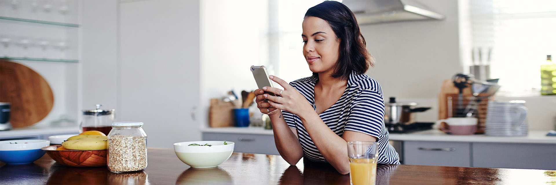 Woman at the kitchen table holding her phone