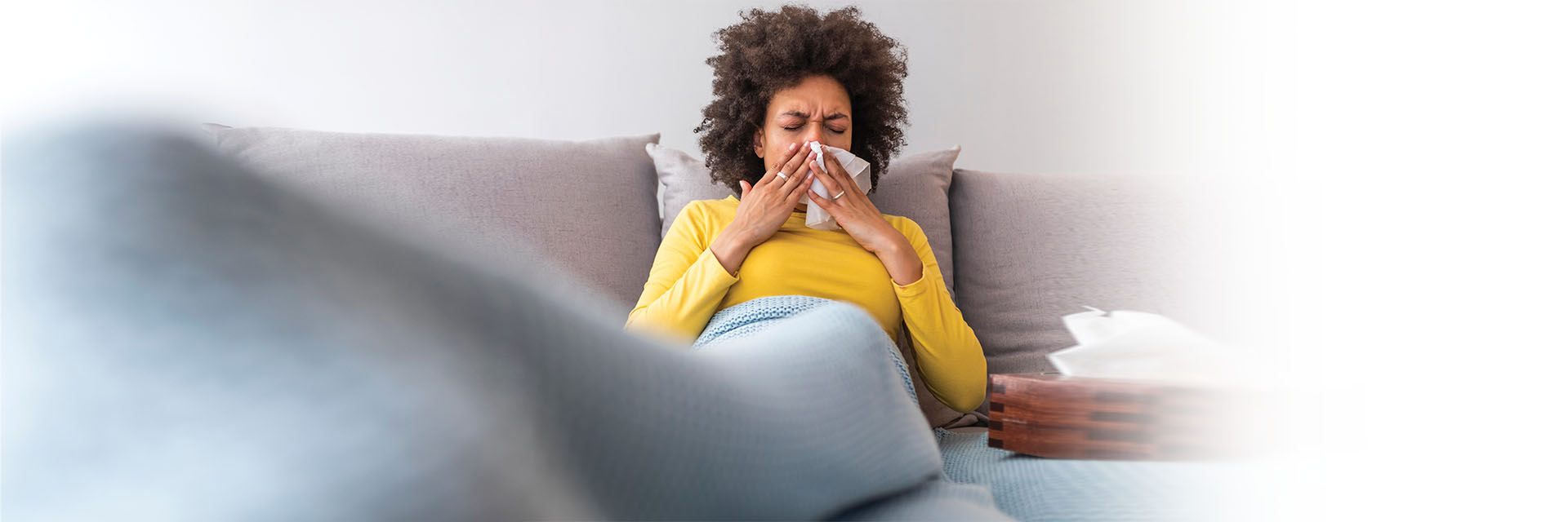 Woman sick on her couch wrapped in a blanket